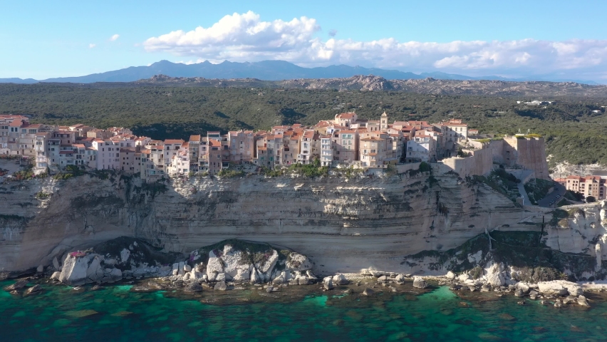 France, Corse, Bonifacio, drone aerial view during a beautifull sunny day, with famous houses by the cliffs, green moutains in back