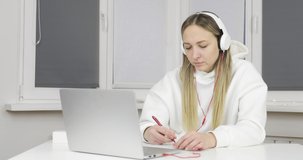 Online lesson. A woman in white headphones communicates via video call. Study and work remotely. Quarantine. Epidemic.