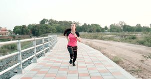 Tracking shot, Young Asian woman is exercising with outdoor running On the road covered with bricks, Concept healthy running and outdoor exercise, Female model runs towards the camera