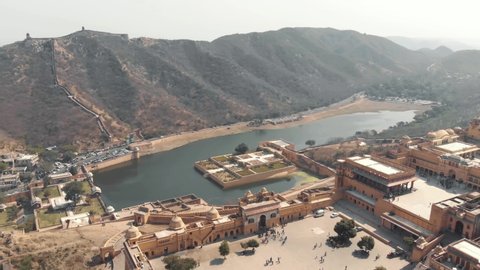 Maota Lake overlooked by Amber Fort embellished with Kesar Kyari Garden in Jaipur, Rajasthan, India - Aerial Fly-over shot