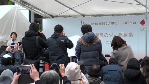 FUKUSHIMA, JAPAN - 24 MAR 2020 : Crowd of people at Olympic Flame display ceremony at Fukushima station. Tokyo Olympic 2020 have been postponed to 2021 due to coronavirus. Many people wearing masks.