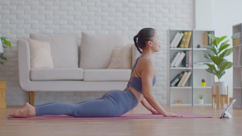 Wellness Attractive Asian woman practice yoga Cobra pose online course at home to meditation comfortable and relax,Yoga online class Exercise at home Concept,Self-isolation due COVID-19 pandemic
