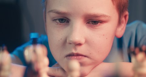 Cute little boy playing chess at home. Smart kids. Game good for brain intelligence concept. Clever concentrated and thinking child while playing chess. Kids early development. Figures on chessboard.