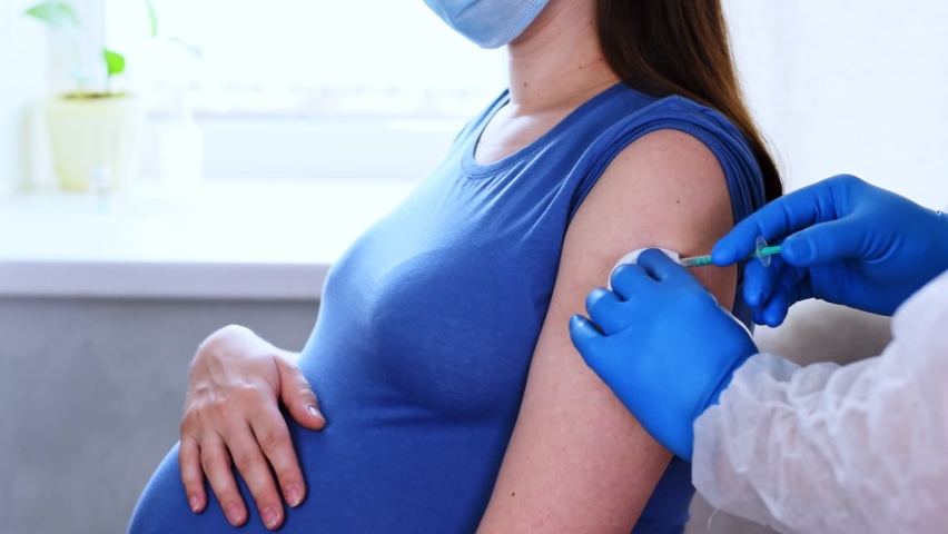 Pregnant Vaccination. Doctor giving COVID -19 coronavirus vaccine injection to pregnant woman. Doctor Wearing Blue Gloves Vaccinating Young Pregnant Woman In Clinic. People vaccination concept. Slow Royalty-Free Stock Footage #1071348319