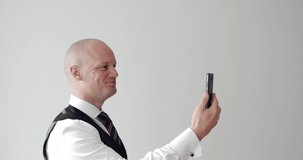 Portrait of smiling young businessman in formal clothes standing inside using mobile phone. elegant Man on white background talking and video meeting on mobile phone. zoom call, working from home, 