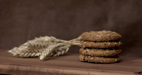 Wheat fall on dietary cookies on a wooden table on a dark background. Filmed high speed cinema camera, slow motion. 4K.