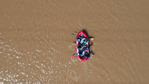 Bright red boat moves on the surface of a muddy river. Paddle for rowing. The glare of the sun is reflected on the surface of the water. High quality. 4k footage