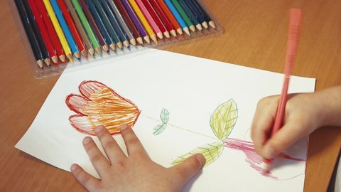 Children's hands draw a symbolic flower in a vase with a pencil close-up. The concept of children's creativity, online education. Leisure of a happy child, quarantine and isolation. View from above.
