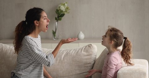 Female speech therapist teaching sound pronunciation to little cute girl. Young mother and her daughter do vocal exercises, learn pronouncing words correctly, voice ability problem correction concept