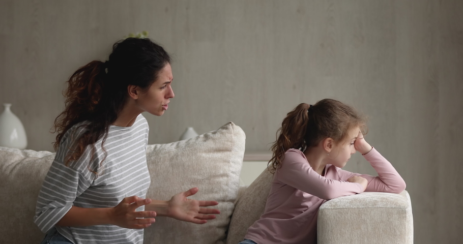 Irritated young mother scolds preschool kid girl for bad behavior and disobedience while sit on sofa, raising voice, scream at her little daughter. Difficulties of upbringing, misbehaved child concept | Shutterstock HD Video #1071353866