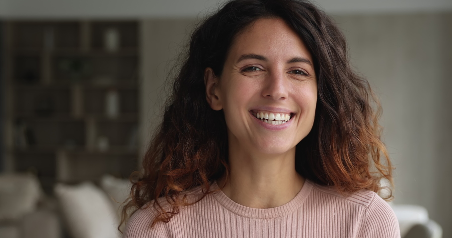 Head shot close up face view gorgeous woman standing indoor smiling looking at camera. Portrait of beautiful female having wide smile with straight perfect teeth advertise dental services concept | Shutterstock HD Video #1071353917