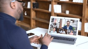 Remote meeting concept. An African-American male employee involved in video conference with group of multiracial colleagues online, diverse workteam on the laptop screen talking on the distance