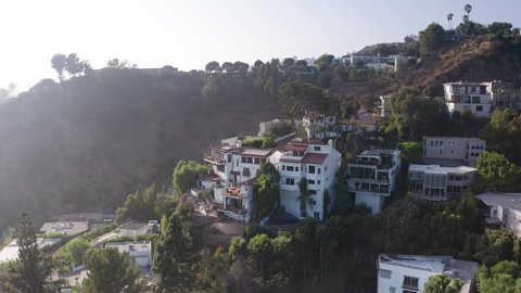 Aerial rising shot tilting down on mansions dotting the hillside in Beverly Hills. 4K