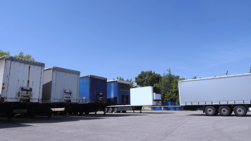 White lorry with cargo trailer drives back into parking place and parks with other cargo trailers. Royalty-Free Stock Footage #1071381490