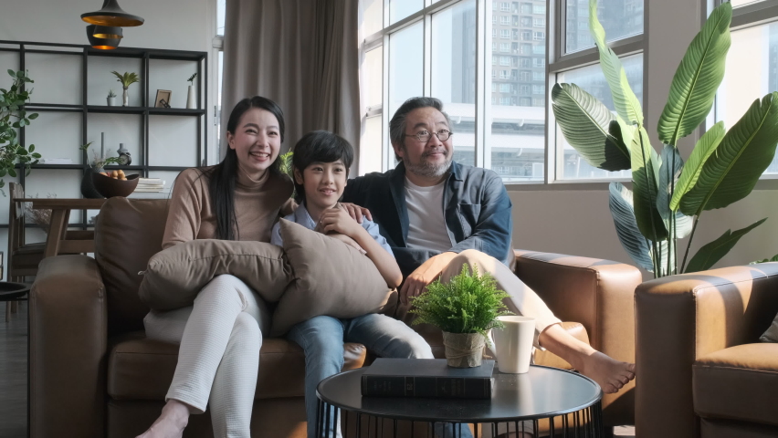 Happy Asian family spending time by watching tv together on sofa in living room. family and home concept | Shutterstock HD Video #1071382315