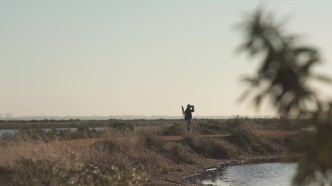 ornithologist at sunset observing birds with binoculars in marshes,
natural place