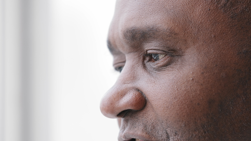 Extreme facial close up mature african middle aged man 50s male eyes with wrinkles looking in distance out window thinking dreaming, enjoying good eyesight after successful laser correction operation | Shutterstock HD Video #1071383206