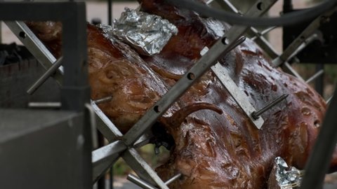A detailed view of a roasted pig carcass spinning on a spit. Street food, closeup.