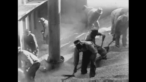 CIRCA 1940s - Laborers shovel wheat into a pipe at the mill in 1944.