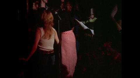 CIRCA 1973 - In this exploitation movie, members of a rock band make eyes at women dancing to their music at a nightclub.