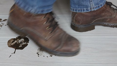 A man in dirty shoes walks across the clean, light floor. The man left traces of dirt from his boots.dirty shoe marks
