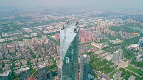 Suzhou, China - September 04, 2020: Aerial view of a skyscaper under construction with reflections on the glass windows in a business district of Suzhou, China. IFS building. Camera moves forward.