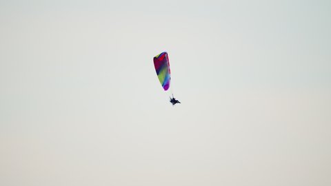 Aerial view of Skydiver flying against the clear sky. Colorful canopy of a parachute. Concept of travel and leisure. A man flying under the canopy of a parachute. Paraglider during the daytime. 