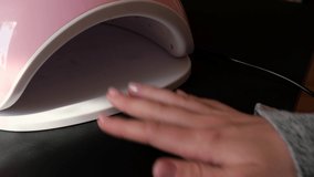 4k video led lamp Beauty salon visitor dries base gel on ultraviolet lamp. Nail care, Self care. Do manicure by yourself while stay at home. Diy. Manicure tools