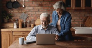 Overjoyed loving sincere mature senior married couple looking at laptop screen, reading email with amazing news, celebrating online lottery win or internet success, feeling joyful together at home.