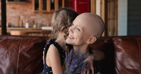 Happy little kid girl presenting bunch of lavender flowers to smiling mother with bald head, congratulating with cured oncology disease or International Women's Day, showing care love and support.