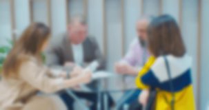 Unrecognizable people who are holding a business meeting or negotiation. Blurry defocused video. Business theme background.