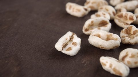 Puffed spelt wheat on a dark wooden background. Uncooked cereal. Macro. Dolly shot