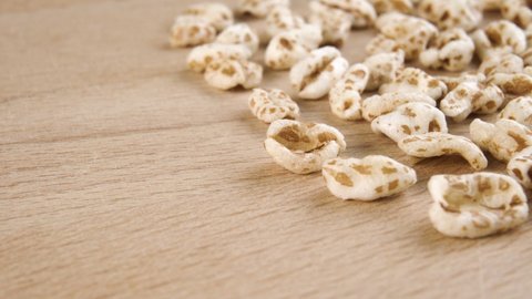 Puffed spelt wheat on a wooden cutting board background. Uncooked cereal. Macro. Dolly shot