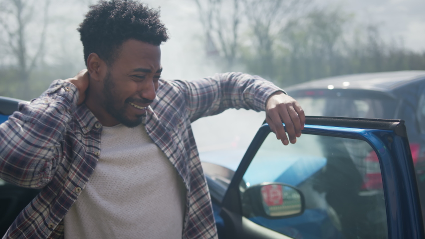 Young man rubbing neck in pain from whiplash injury getting out of car and standing by damaged car after traffic accident - shot in slow motion Royalty-Free Stock Footage #1071408892