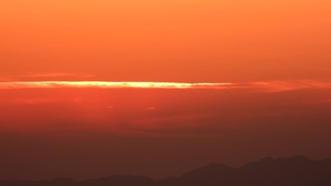 Sunrise sun rising in hazy air below the thin orange cloud line. Sunup at dawn twilight early morning day before after time bare simple cinematic background landscape view nature fog mist haze moist 4K