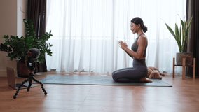Asian woman yoga teacher filming yoga online class on video for Social media. Professional instructor in sportswear posing on VIDEO camera. Healthy lifestyle - technology at home. New normal lifestyle