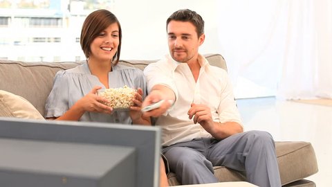 Young couple watching tv with popcorn in the living room