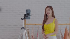 Entrepreneur of Asian young woman live streaming video online for selling her dress and clothes to customer in platform or application online,Influencer cute girl reviews and presenting cloths at home