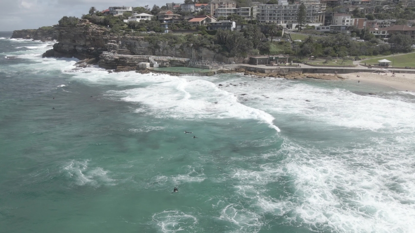 People On Their Surfboards Are Adrift By Breaking Waves At Bronte Beach With Bronte Baths In Sydney, Australia. - Aerial Drone Shot