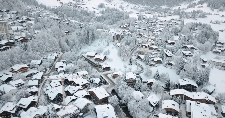 Drone shot over Swiss, traditional ski village. Morning traffic, following heavy snow fall. Cars in snow