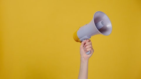 Cropped shot of unrecognizable woman hold in hand bullhorn public address megaphone, hot news announce discounts sale hurry up communication concept, isolated on yellow wall with copy space mock up