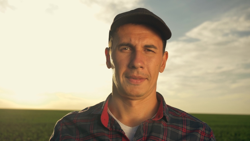Farmer agronomist in the field at sunset. Ecoculture farm. Senior farmer, business owner looks at the camera in the field. Senior agronomist adjusts his cap and hat. Farmer agronomist checks eco-crops Royalty-Free Stock Footage #1071427630