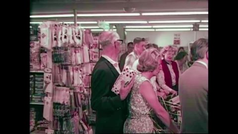 CIRCA 1960s - Chaos ensues in an overcrowded supermarket as a couple hauls their shopping cart up the stairs to a train station in the 1960s.