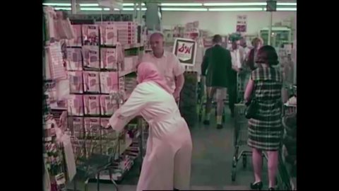 CIRCA 1960s - A woman keeps trying to get down aisles at the grocery store, but they are all overcrowded in the 1960s.