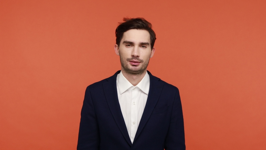 I am a King! Selfish proud businessman wearing crown and folding hands, looks at camera with confident satisfied expression considers himself the best. Indoor studio shot isolated on orange background