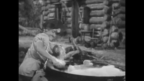 CIRCA 1940 - In this comedy movie, a hillbilly tickles her husband by scrubbing his feet in the bath.
