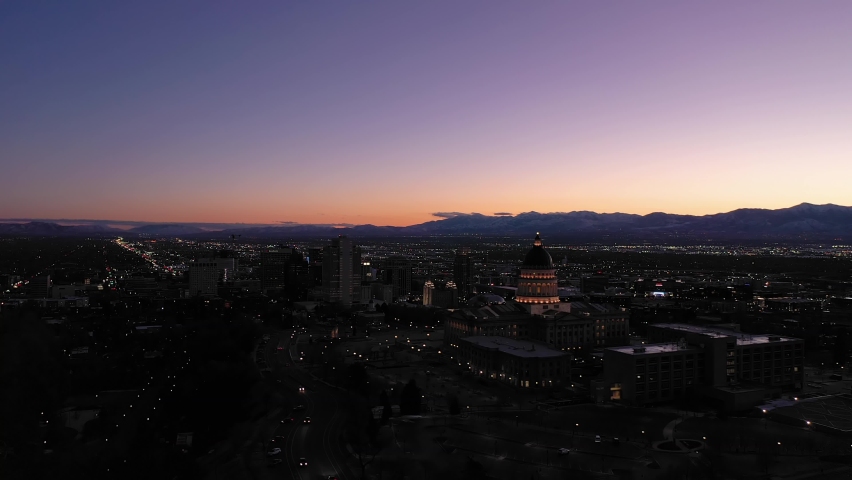 Illuminated Salt Lake City Skyline at Sunset in Evening Twilight in Winter. Capitol Hill. Utah, USA. Aerial View. Blue Hour. Drone Flies Sideways and Upwards