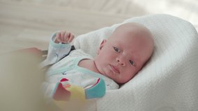 Closeup face of adorable baby boy, portrait of cute 1.5 month old caucasian baby lying on white baby bouncer. High quality 4k footage