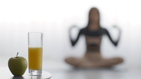 Healthy Lifestyle Concept. Apple And Orange Juice Lying On Floor While Unrecognizable Black Woman Meditating Sitting In Lotus Position Doing Yoga At Home. Selective Focus, Shallow Depth