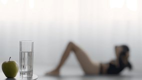 Weight Loss Diet And Workout Concept. Unrecognizable Woman Doing Abs Crunshes On Floor, Standing Up And Taking Glass Of Water For Healthy Hydration During Training At Home. Selective Focus
